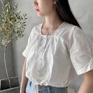 Detail of a white pleated collar shirt with drawstring hem and cotton linen texture