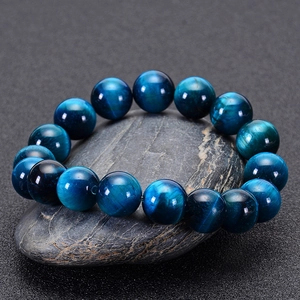Detailed close-up of blue tiger eye stone beads arranged on a grey stone surface