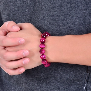 Macro detail of rose red tiger eye stone bracelet beads with shimmering cat eye effect