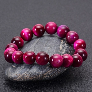 Macro detail of rose red tiger eye stone bracelet beads with shimmering cat eye effect