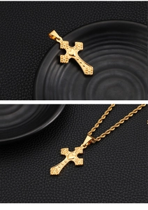 Detail of a golden cross necklace with heart and floral patterns on black leather background