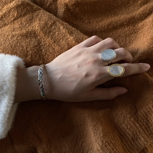 Minimalist silver and gold rings with oval shells and a textured woven bracelet