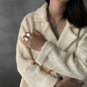 Close-up of minimalist 925 sterling silver shell rings and vintage coin necklace on a model