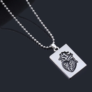 Macro shot of silver ball chain necklace featuring anatomical heart engraved pendant