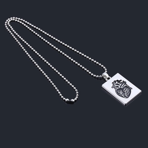 Detailed view of silver bead chain necklace with black anatomical heart pendant on black background