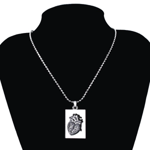 Macro shot of silver ball chain with anatomical heart pendant on black neck bust display