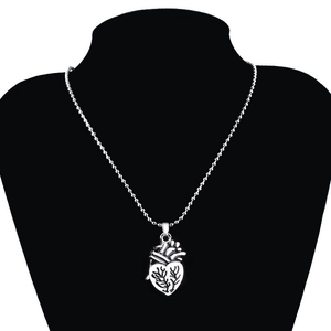 Detail of silver heart pendant with branch textures on black mannequin stand