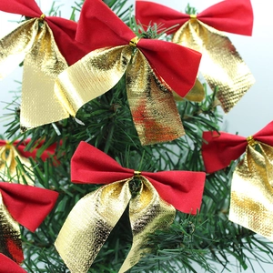Christmas 8cm red and gold velvet ribbon bows hanging on green pine tree branch