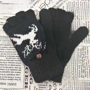 Détails de gants tricotés noirs avec motif renne blanc et bouton marron de près