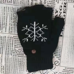Gros plan de gants tricotés noirs avec motif flocon de neige sur fond de journal