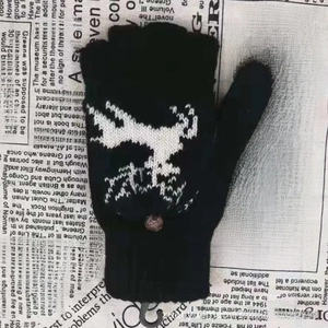 Gros plan des gants sans doigts en laine noire avec motifs rennes et bouton décoratif