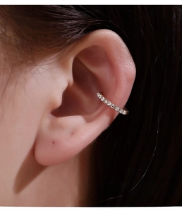 Detail showing a silver ear cuff with white cubic zirconia worn on a woman's ear cartilage