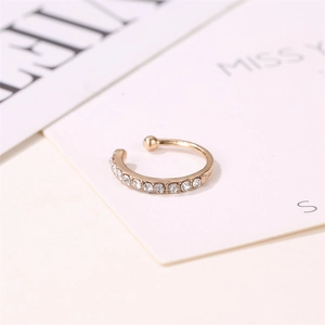 Close-up of gold-plated ear cuff with sparkling white rhinestones on white background
