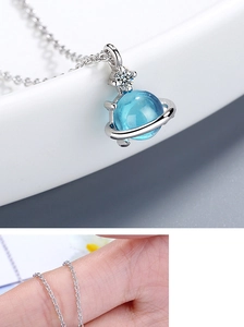 Macro detail of blue planet pendant with white zircon on elegant silver chain