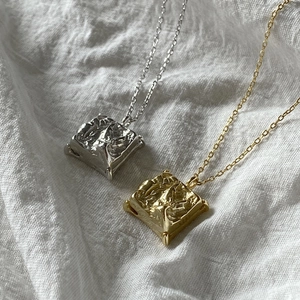 Macro shot of 925 sterling silver square pendants with irregular lava texture finish