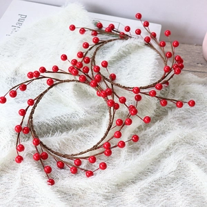 Artificial red berry wreath with glossy berries and brown stems on white fur background