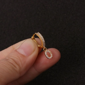 Nahaufnahme eines goldenen Creolen-Ohrrings mit einem Zirkonia-Buchstaben-O-Anhänger