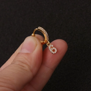 Nahaufnahme eines goldenen Ohrrings mit Zirkonia-Steinen und einer Nummer 6 als Anhänger