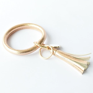 Detail of rose gold O-ring keychain with leather tassel and spring clip on white background