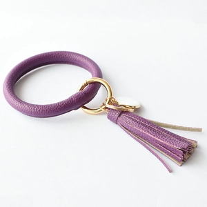 Close-up of a purple faux leather circle keychain with a gold clasp and purple tassel