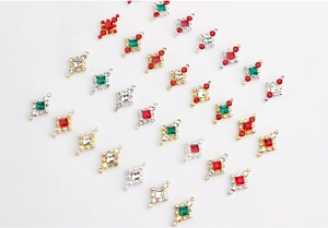 Détail de bijoux d'ongles losanges avec pierres rouges vertes et perles sur base d'or