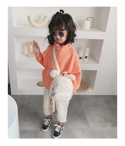 Petit enfant portant un sweat à capuche orange et un joli sac à dos ours en peluche blanc