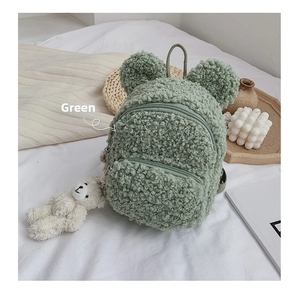 Détail d'un sac à dos enfant en polaire verte avec oreilles d'ours et peluche ours