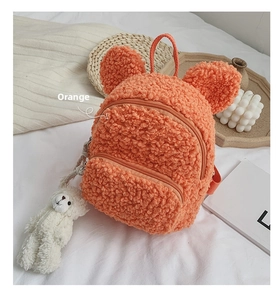 Détail d'un sac à dos enfant en polaire orange avec oreilles mignonnes et pendentif peluche