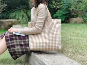 Borsa tote in tela a quadri marroni e bianchi con manici in pelle in ambiente esterno