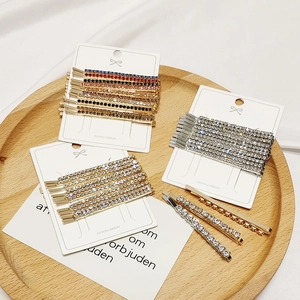 Detailed close-up of rhinestone hair clip set in gold and silver on a wooden tray