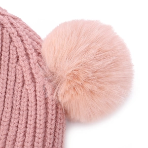 Close-up of pink knit baby hat featuring chunky texture and soft faux fur pom-pom detail