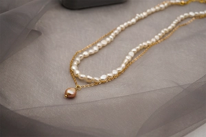 Détail d'un collier de perles baroques à deux rangs avec pendentif perle sur tulle gris