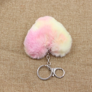 Detail of pink and yellow gradient heart plush keychain on rustic burlap background