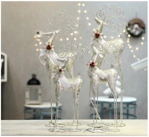 Close-up of golden and silver metal reindeer statues with scarves and festive berries