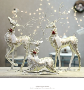 Detail of glittery Christmas deer ornaments with white scarves and red berries
