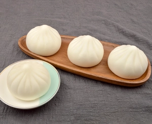 Macro detail of squishy 7cm steamed bun food models on rustic wooden and ceramic trays