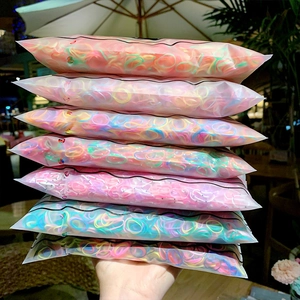 Colorful elastic hair bands in resealable packaging stacked on a wooden outdoor table