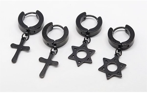 Detail of matte black stainless steel hoop earrings with cross and star pendants