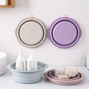 Space-saving foldable plastic basins in beige, purple, and blue hanging on bathroom wall