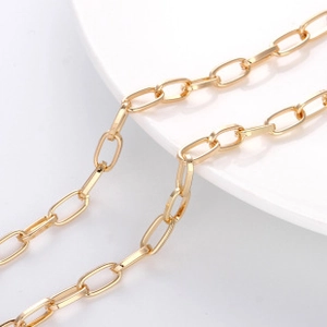 Detail of polished gold paperclip link chain with a glossy metallic finish on white tray