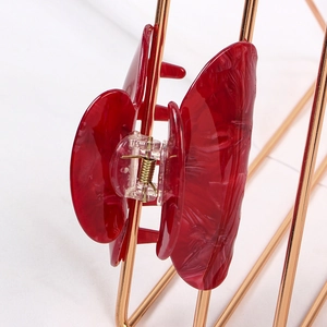 Macro view of red marble texture hair claw clip with strong gold metal spring detail
