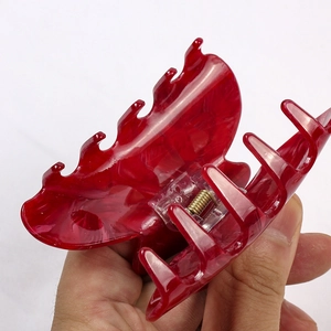 Close-up of translucent red acetate hair claw clip held in hand for size comparison