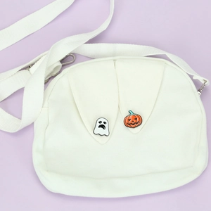 Detail of white canvas bag with ghost and pumpkin pins on bunny ear flap pockets
