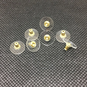 Golden bullet clutch earring backs with clear plastic pads scattered on black mesh