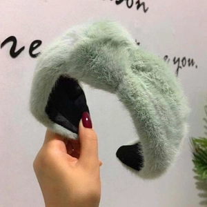 Dettaglio di una fascia per capelli annodata in morbido peluche verde menta per l'inverno.