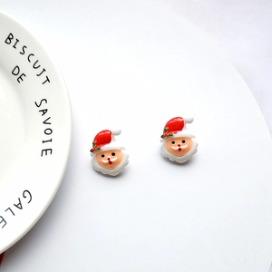 Close-up of handmade Santa Claus resin earrings on a decorative white porcelain plate