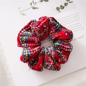 Macro detail of red tartan Christmas scrunchie with snowflake patterns on fabric