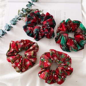 Detail of four festive Christmas plaid scrunchies with red and green snowflake patterns