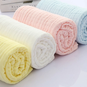 Close-up of rolled ultra-soft pure cotton baby towels in yellow, white, pink and blue
