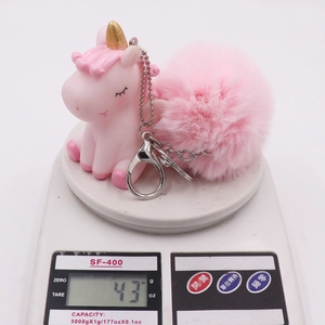 Pink unicorn keychain with soft pom pom and lobster clasp on a digital scale